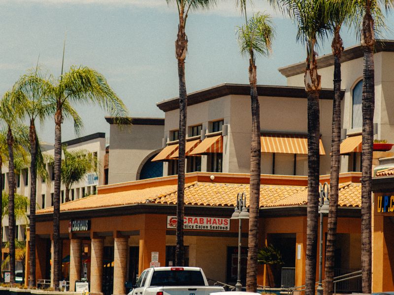A shopping center with palm trees and pickup trucks in the lot
